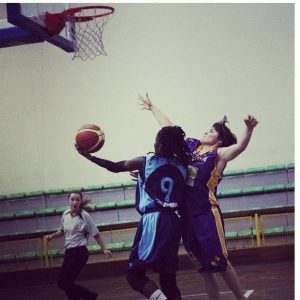 Corin "Tiny" Adams (In blue uniform) takes it to the basket for a layup. 