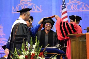 Authorine Foster receiving her honorary  Doctorate degree from President David Wilson as Reverend Jesse Jackson looks on. Photo by Benjamin McKnight III