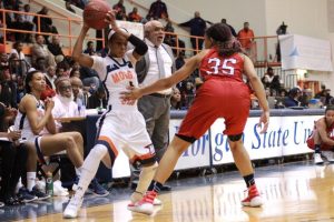 Breannan Farrar attempts to make a move with the ball as former head coach Donald Beasley gives orders in the background. Photo by Terry Wright.