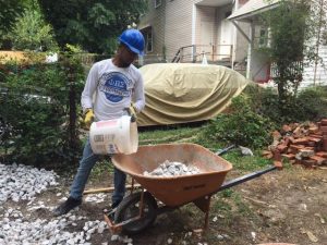 Senior Ricco Peña fills a wheelbarrow with rocks while volunteering with Habitat for Humanity. Photo by Jazmine Hawes.